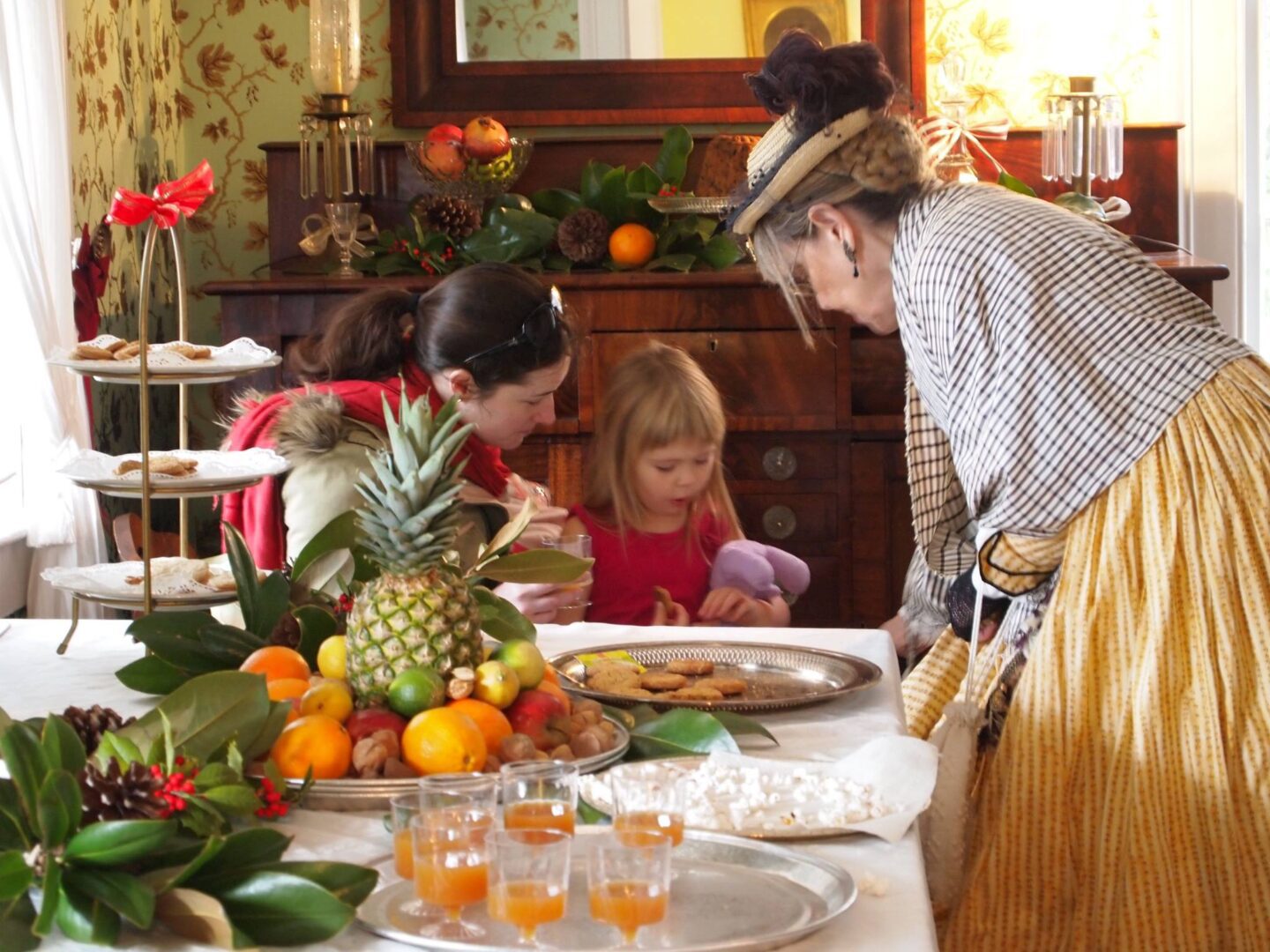 A group of women and children looking at a table full of food.