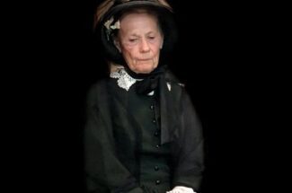An old lady in a black dress and hat.